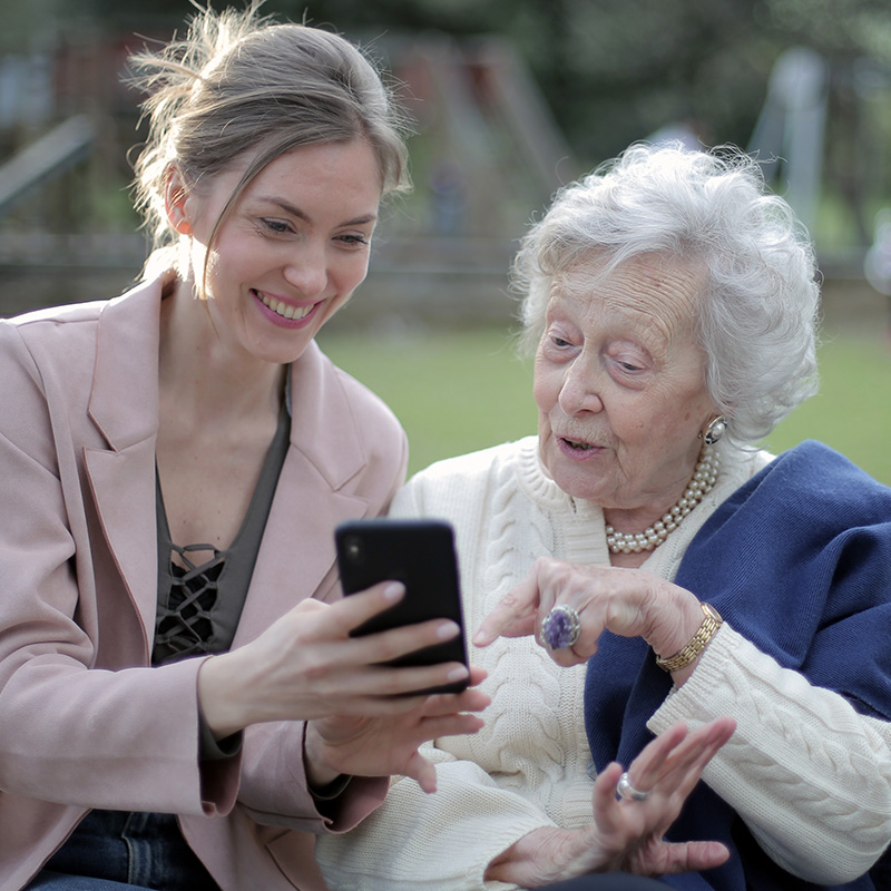 Older and younger women on a park bench