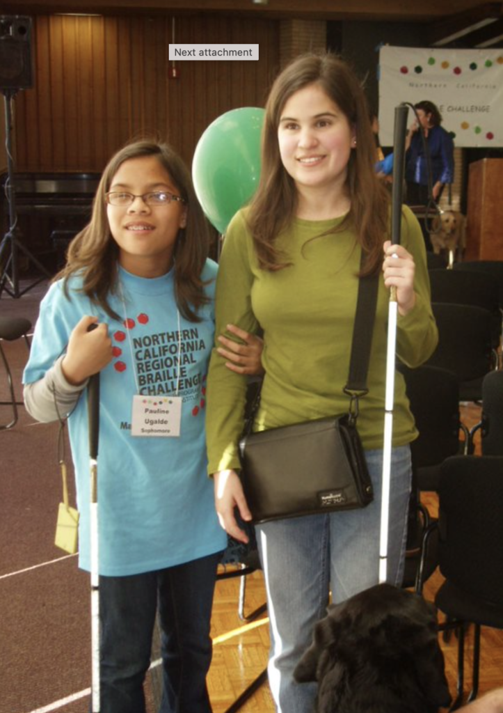 Two students linking arms and holding white canes