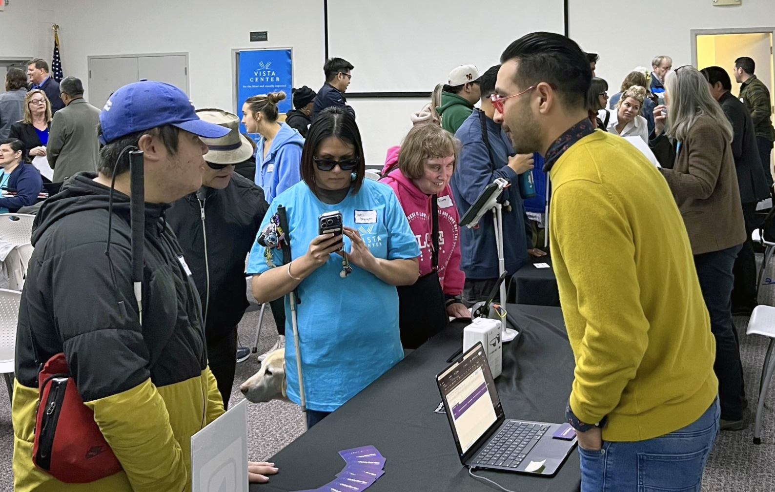 ViddyScribe representative stands at their entrepreneur table and is engaged in conversation with four guests.